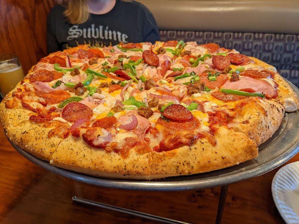 Printed menu with pizzas, sides, and drinks.